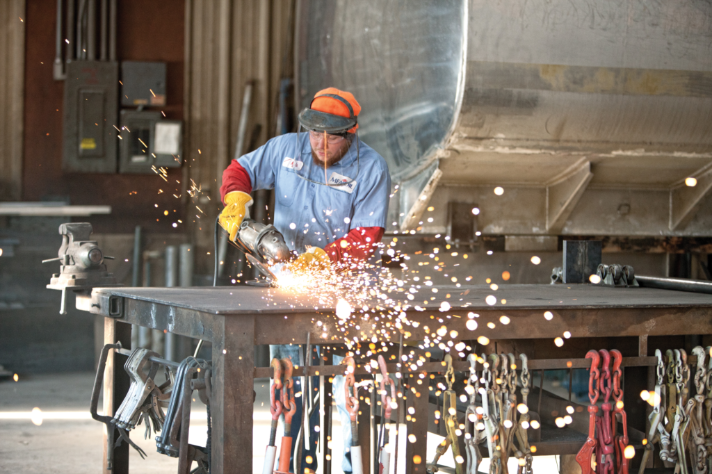 Kyle Burton uses a grinder on a part for the truck shop. Right: Kyle Strodtman washes a refined fuel tank wagon. Stacy Raps checks the register on a propane truck.