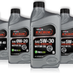 Four bottles of motor oil are displayed, showcasing the Excede brand lubricants. Each bottle is labeled with different viscosities: SAE 10W-40, SAE 0W-20 Full Synthetic, SAE 5W-30 Full Synthetic, and SAE 5W-20 Synthetic Blend. The MFA Oil branding is prominent on each bottle.