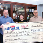 Three people smiling and holding a large ceremonial check for $16,415.22 made out to the Food Bank for Central & NE Missouri. The check is presented by MFA Oil, Big O Tires, and Jiffy Lube. The event date is November 16, 2018.