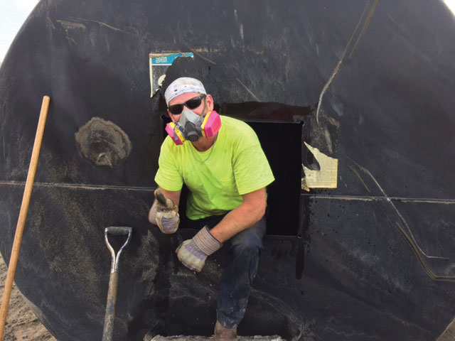 Keller Colley, senior EH&S compliance administrator, cleans out an underground storage fuel tank for disposal. Discarded tanks are frequently sold to scrap yards.