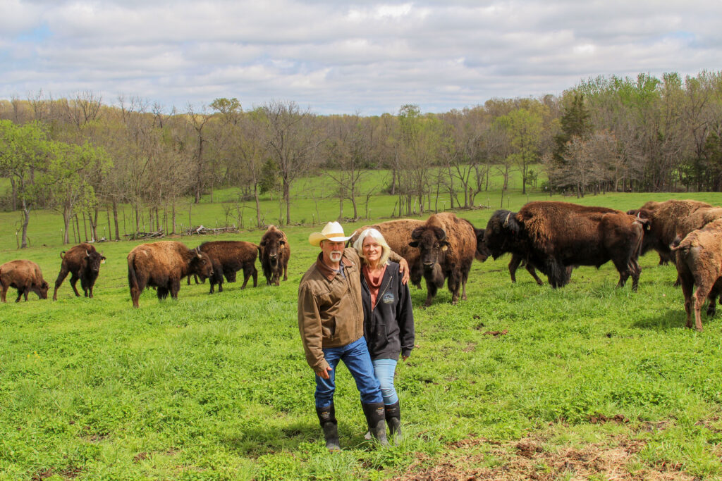 IMG_7740-2 C.J. and Tina Gallen share a moment amid their bison herd at Cedar Stone Ranch in Lenox, Mo. The Gallens have forged close bonds with their bison, allowing them to move safely among the herd.