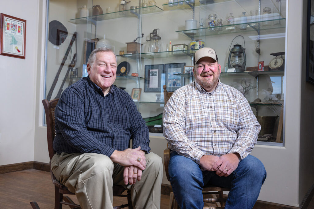John and Andy Clay sit in front of a display case that holds family heirlooms.