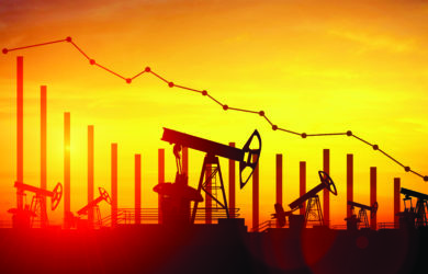 Silhouetted oil pumpjacks in a field at sunset with a descending graph line overlaid, indicating a decrease in oil production or prices.